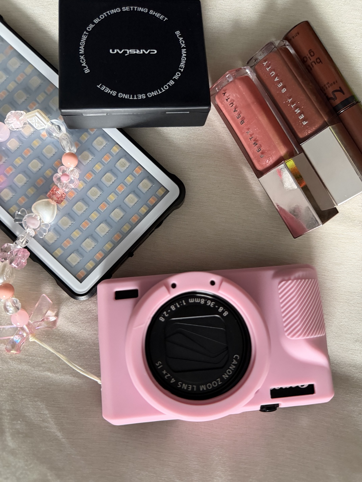 Beauty products and a pink camera arranged for the beginner makeup kit video